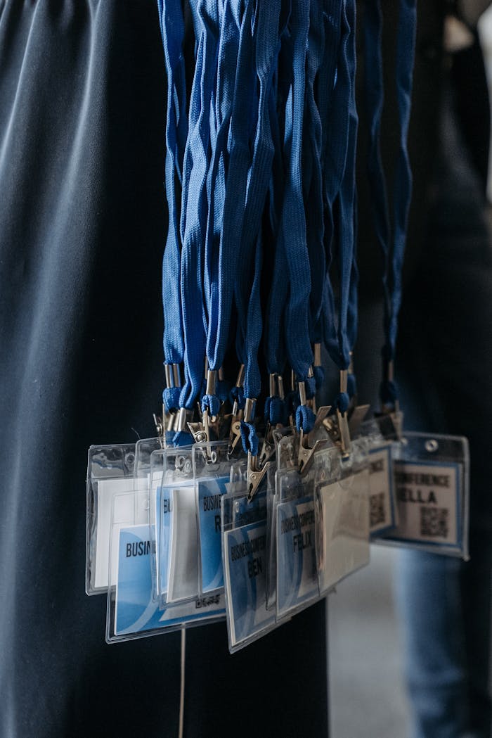 Close-up of blue lanyards with identification badges at an event.
